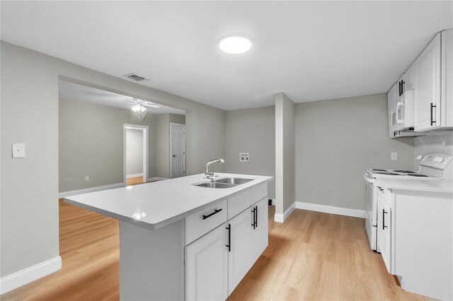 kitchen with white appliances, white cabinetry, sink, and a kitchen island with sink