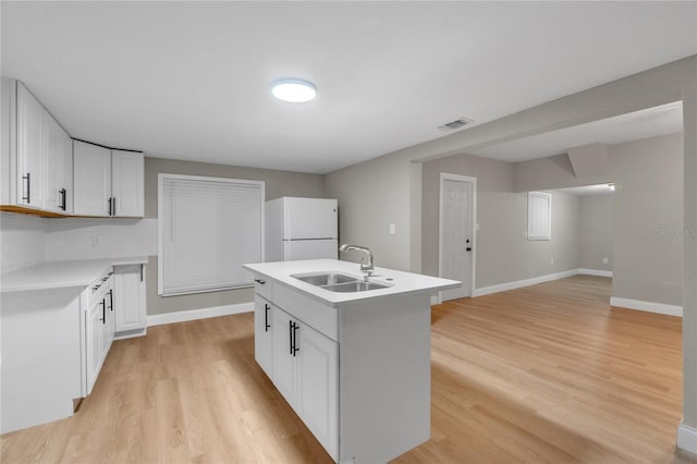 kitchen featuring light countertops, a sink, freestanding refrigerator, and white cabinets