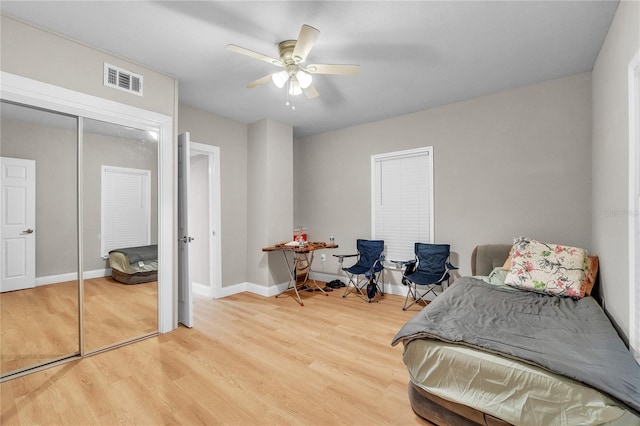 bedroom with a closet, visible vents, ceiling fan, wood finished floors, and baseboards