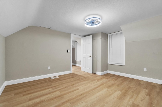 bonus room featuring light wood-style floors, baseboards, visible vents, and a textured ceiling