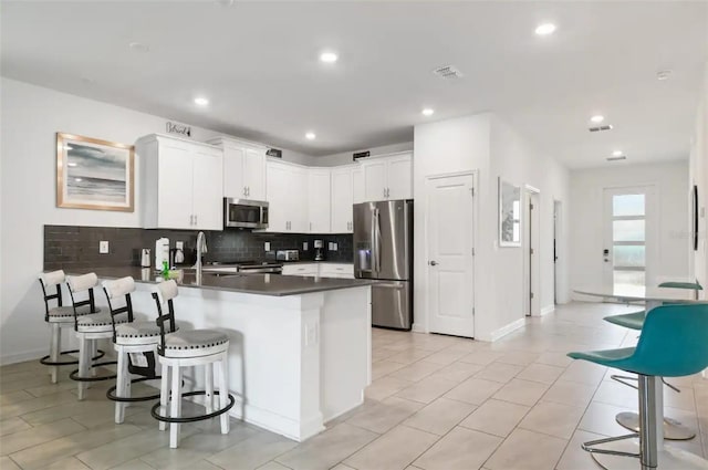 kitchen with appliances with stainless steel finishes, decorative backsplash, sink, white cabinets, and kitchen peninsula