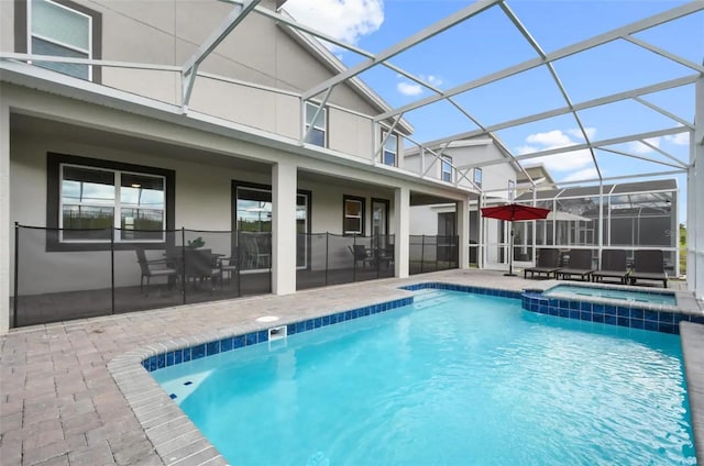 view of pool featuring glass enclosure, a patio area, and an in ground hot tub