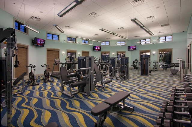 workout area featuring a drop ceiling, carpet, and a towering ceiling