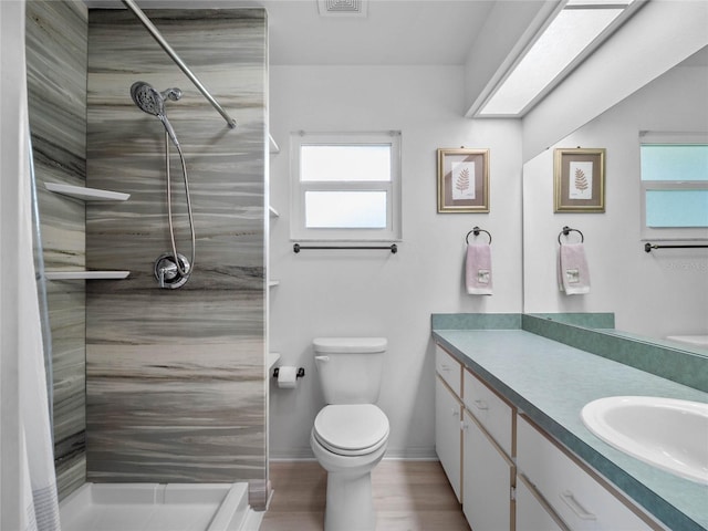 bathroom featuring vanity, toilet, a tile shower, and wood-type flooring