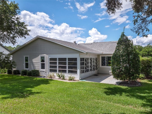 back of property with a lawn, a sunroom, and a patio