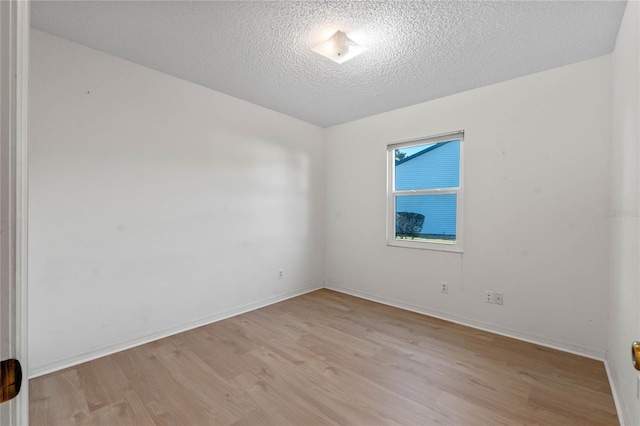 empty room with light hardwood / wood-style floors and a textured ceiling