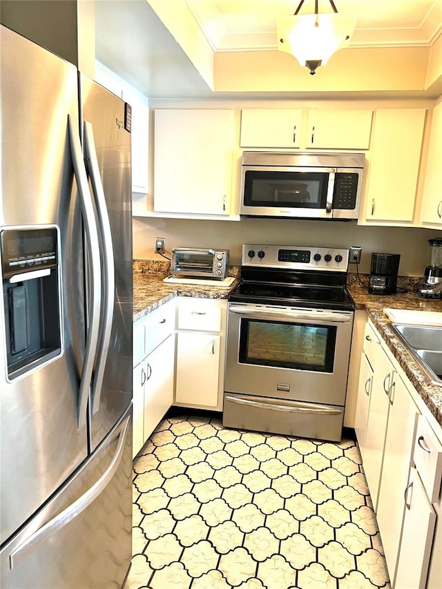 kitchen featuring stainless steel appliances, dark stone counters, sink, ornamental molding, and white cabinetry