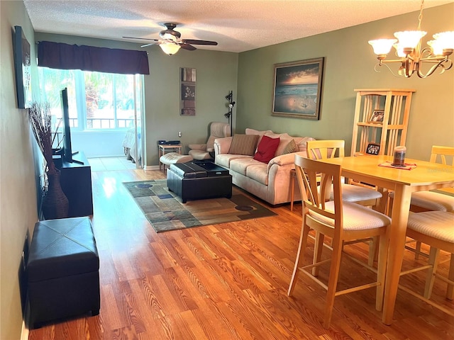 living room featuring a textured ceiling, hardwood / wood-style flooring, and ceiling fan with notable chandelier