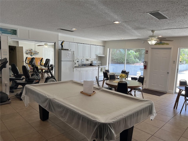 recreation room featuring a textured ceiling, light tile patterned floors, a healthy amount of sunlight, and billiards