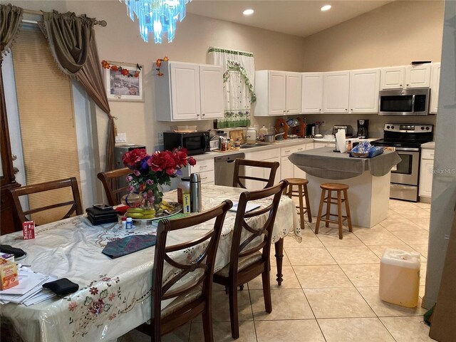 kitchen with white cabinetry, light tile patterned flooring, stainless steel appliances, and a notable chandelier