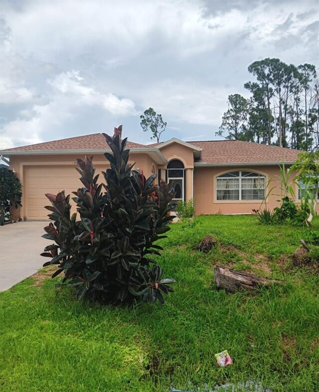 single story home with a garage and a front lawn