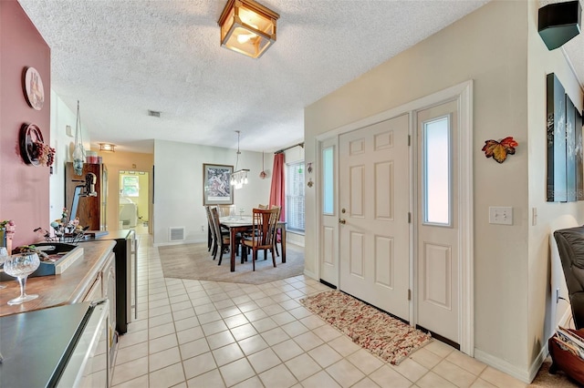 tiled foyer with a textured ceiling, a wealth of natural light, and an inviting chandelier