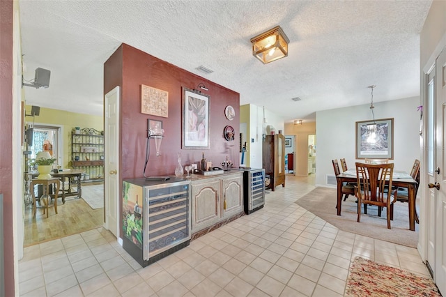 interior space featuring light tile patterned floors, visible vents, wine cooler, and a textured ceiling