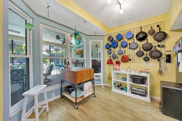 home office with a textured ceiling, baseboards, and wood finished floors