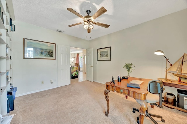 carpeted office featuring a textured ceiling and ceiling fan