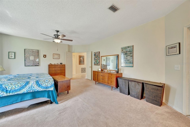 bedroom with visible vents, light carpet, a textured ceiling, and a ceiling fan