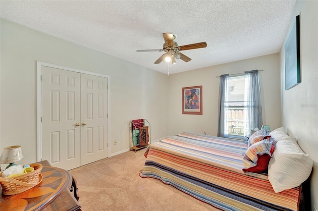 bedroom with a textured ceiling, light colored carpet, ceiling fan, and a closet