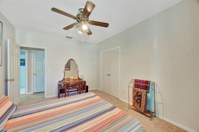 bedroom with visible vents, light colored carpet, a textured ceiling, and baseboards