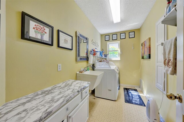 washroom featuring cabinets, a textured ceiling, light tile patterned floors, washing machine and dryer, and sink