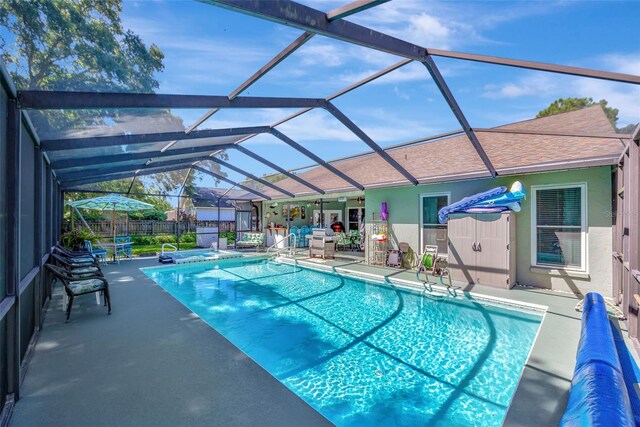 view of swimming pool with glass enclosure and a patio