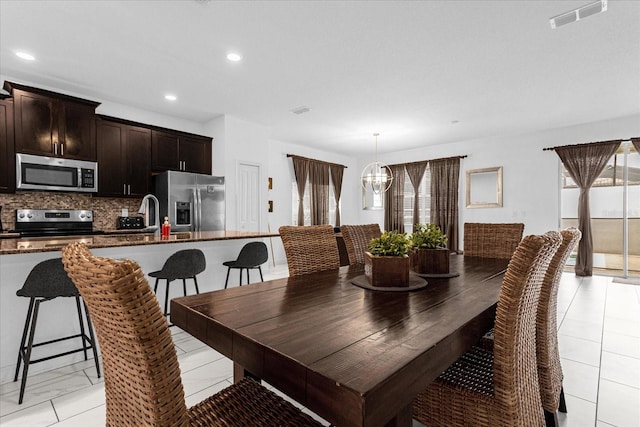 dining room featuring light tile patterned flooring, a wealth of natural light, sink, and an inviting chandelier