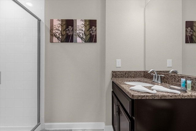 bathroom featuring a shower with door and vanity