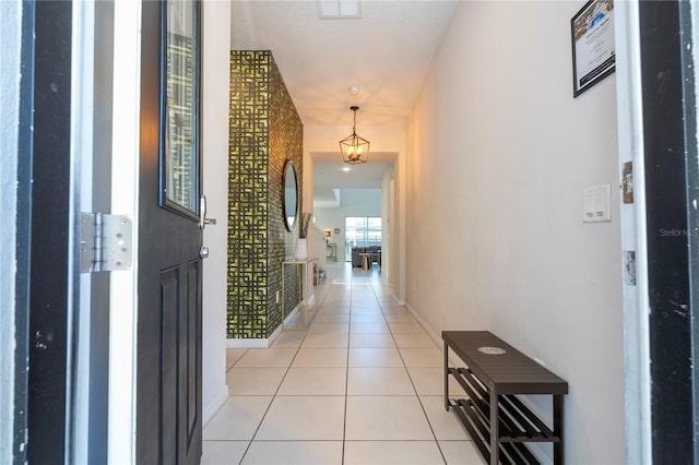 hallway with a textured ceiling and light tile patterned floors