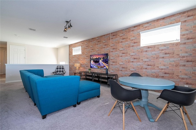 carpeted living room featuring brick wall