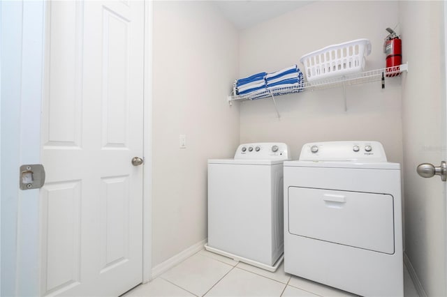 laundry area with washing machine and clothes dryer and light tile patterned flooring