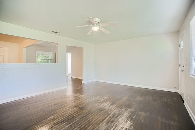 spare room featuring ceiling fan, baseboards, visible vents, and dark wood finished floors