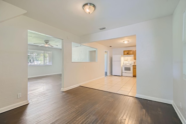 unfurnished room featuring ceiling fan, light wood-type flooring, visible vents, and baseboards