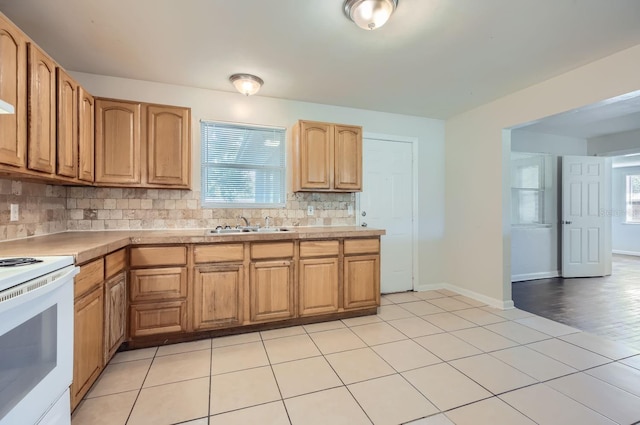 kitchen with sink, decorative backsplash, light tile patterned floors, and white range oven