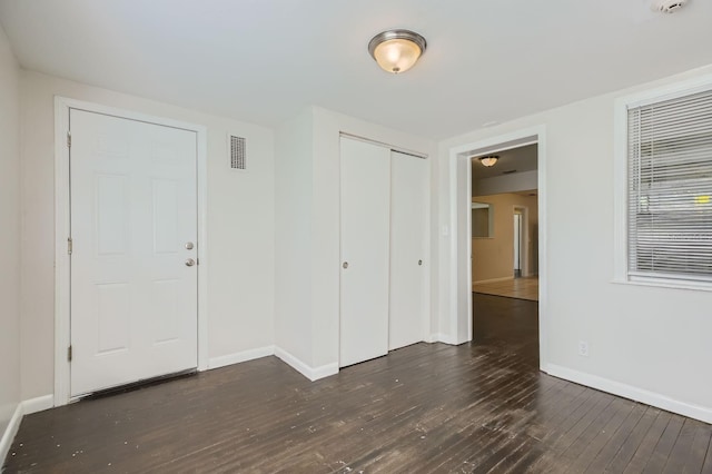 foyer entrance with baseboards, visible vents, and dark wood-type flooring