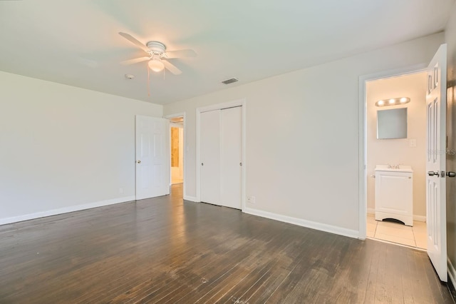 unfurnished bedroom featuring baseboards, visible vents, dark wood-style floors, ceiling fan, and a closet