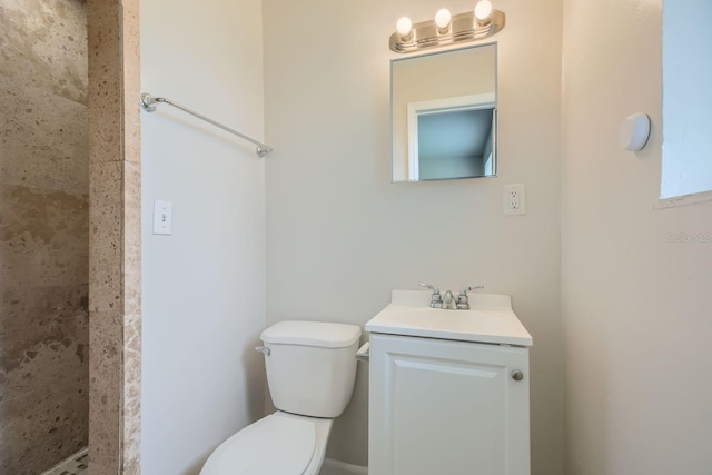 bathroom with tiled shower, toilet, and vanity