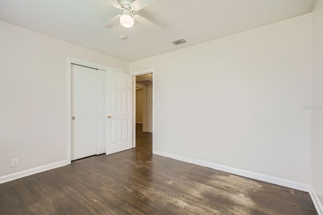 unfurnished bedroom featuring ceiling fan, a closet, and dark wood-type flooring