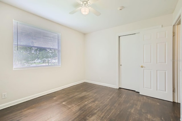 empty room with ceiling fan, dark wood-type flooring, and baseboards