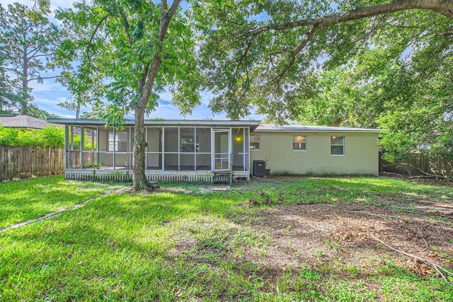 rear view of property featuring a sunroom, central AC, and a lawn