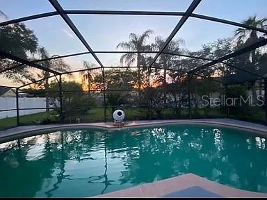 pool at dusk featuring glass enclosure