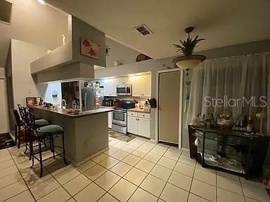 kitchen featuring light tile patterned floors, visible vents, appliances with stainless steel finishes, and a peninsula