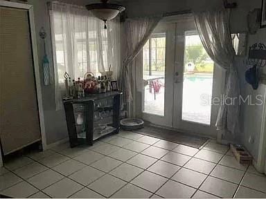 doorway with light tile patterned floors and french doors