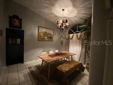 dining area featuring tile patterned floors, a chandelier, and lofted ceiling