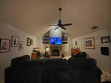 living room with visible vents, lofted ceiling, a brick fireplace, and ceiling fan