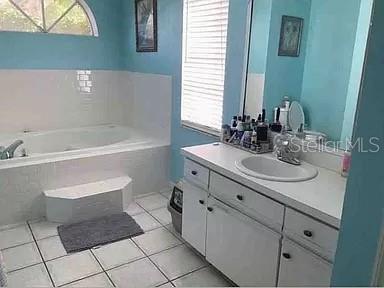 bathroom with tile patterned flooring, vanity, and a garden tub