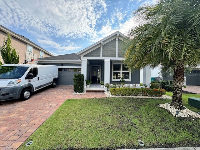 view of front of property featuring a front yard, decorative driveway, a garage, and stucco siding