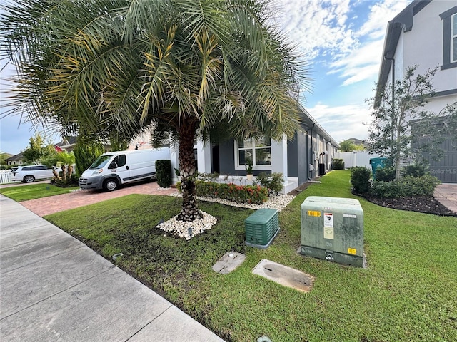 exterior space featuring decorative driveway, a lawn, fence, and stucco siding