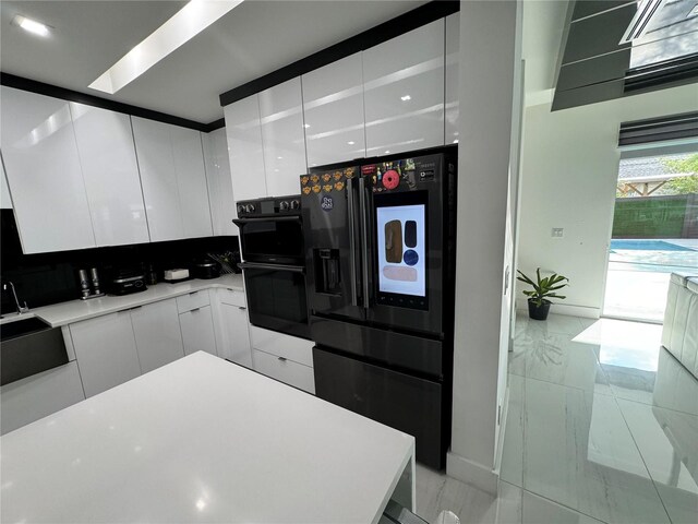 kitchen featuring white cabinetry, light tile patterned floors, and black appliances