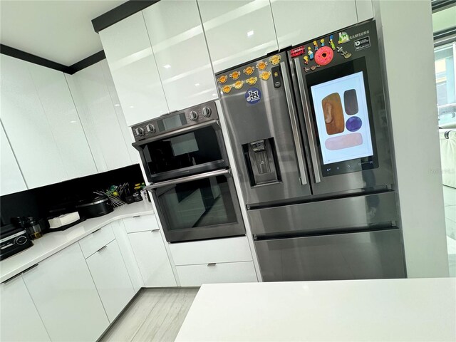 kitchen with double oven, stainless steel fridge with ice dispenser, light wood-type flooring, and white cabinetry