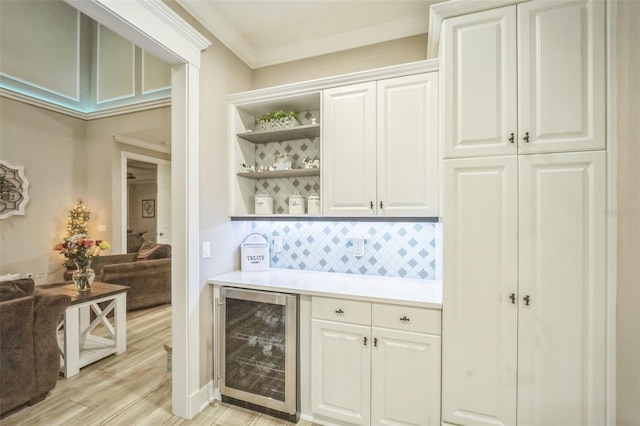 bar with wine cooler, light hardwood / wood-style flooring, tasteful backsplash, crown molding, and white cabinets