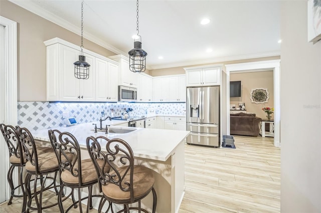 kitchen with appliances with stainless steel finishes, kitchen peninsula, a breakfast bar, tasteful backsplash, and ornamental molding